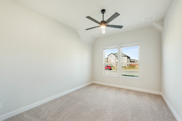 empty room featuring ceiling fan, vaulted ceiling, and carpet floors