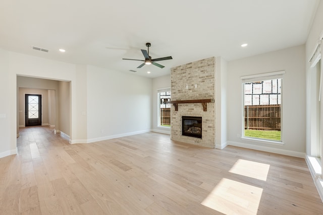 unfurnished living room with a fireplace, ceiling fan, and light hardwood / wood-style flooring