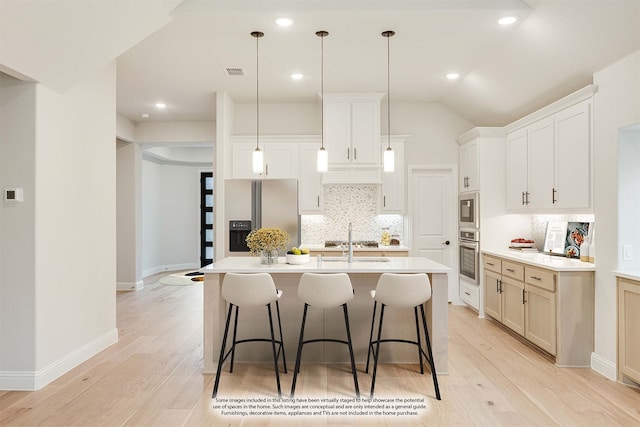 kitchen with light wood-type flooring, stainless steel appliances, sink, a center island with sink, and white cabinetry