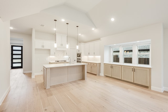 kitchen featuring white cabinets, light hardwood / wood-style flooring, lofted ceiling, and an island with sink