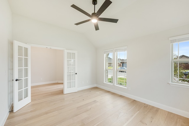 spare room featuring plenty of natural light, lofted ceiling, light wood-type flooring, and french doors