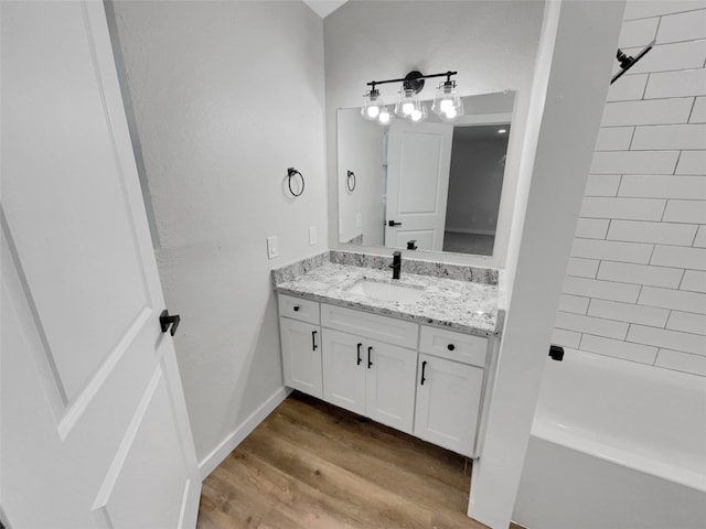 bathroom featuring hardwood / wood-style floors, vanity, and tiled shower / bath