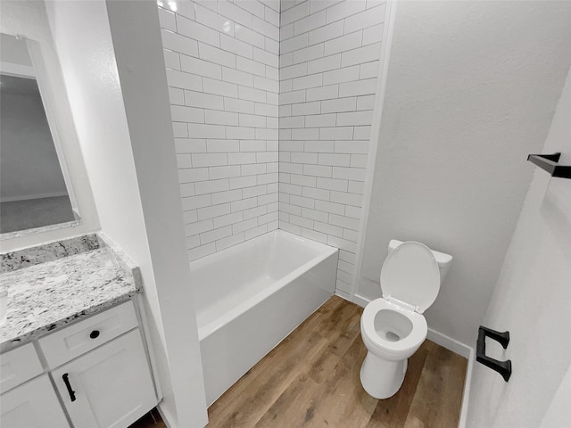 full bathroom with tiled shower / bath, toilet, vanity, and hardwood / wood-style flooring