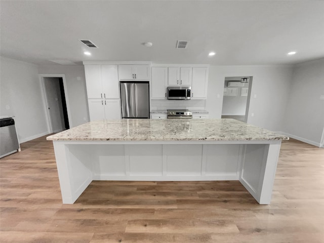 kitchen featuring light stone countertops, stainless steel appliances, light hardwood / wood-style flooring, white cabinetry, and a large island