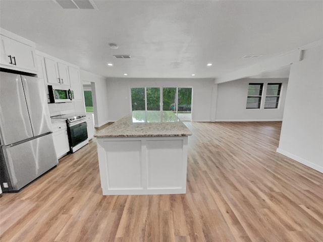 kitchen featuring light stone countertops, white cabinets, light hardwood / wood-style floors, and appliances with stainless steel finishes