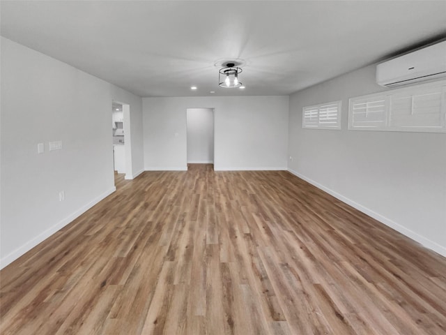 spare room featuring an AC wall unit and light wood-type flooring