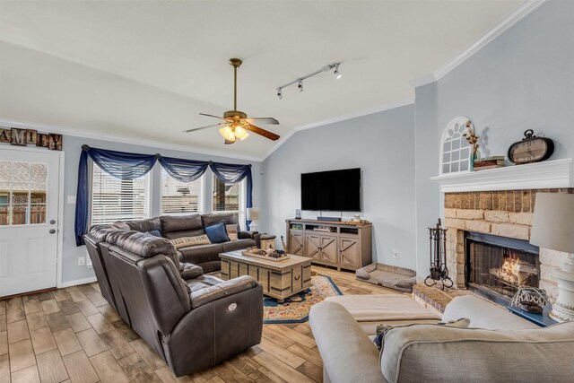 living room with ceiling fan, lofted ceiling, a fireplace, and ornamental molding