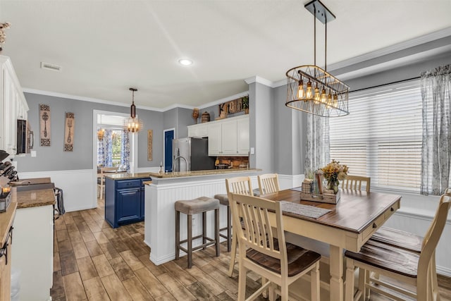 dining space featuring light wood-style floors, a notable chandelier, ornamental molding, and visible vents
