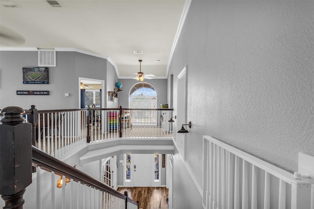 interior space featuring a textured wall, an upstairs landing, visible vents, and wood finished floors
