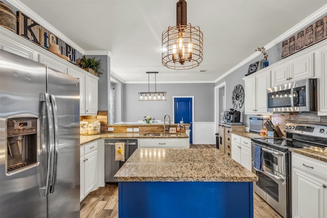 kitchen with a center island, white cabinets, sink, decorative light fixtures, and stainless steel appliances