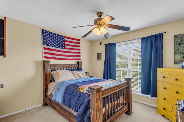 bedroom featuring light colored carpet, baseboards, and a ceiling fan