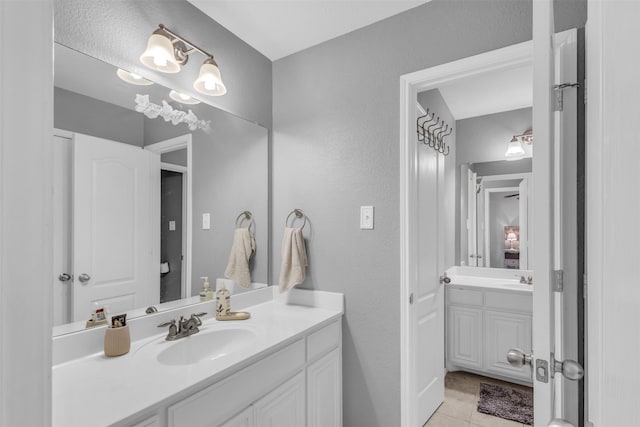 bathroom featuring a sink, tile patterned floors, two vanities, and a textured wall