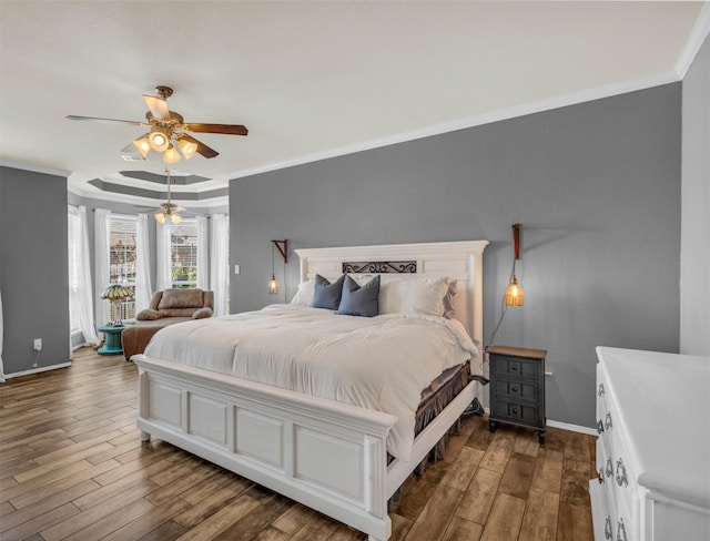 bedroom with ceiling fan, dark hardwood / wood-style flooring, crown molding, and a tray ceiling