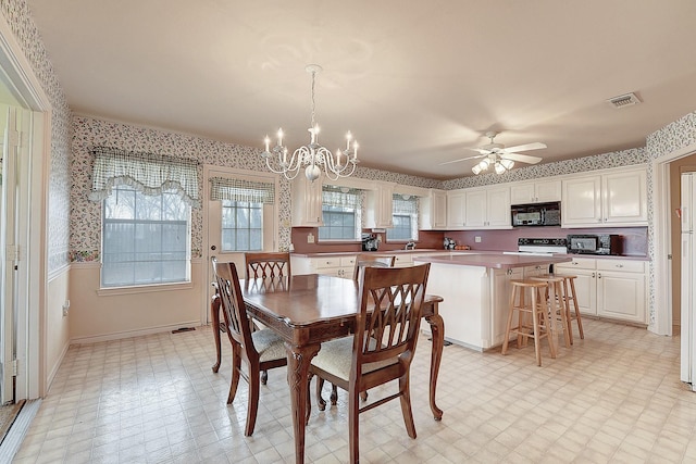 dining space featuring sink and ceiling fan with notable chandelier