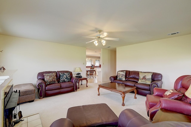 carpeted living room with ceiling fan and a tile fireplace