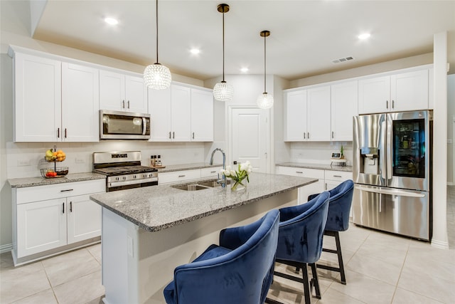 kitchen with white cabinetry, stainless steel appliances, an island with sink, sink, and light tile patterned floors