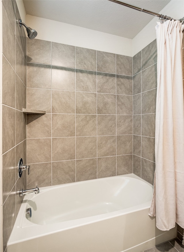 bathroom with shower / bath combo with shower curtain and a textured ceiling