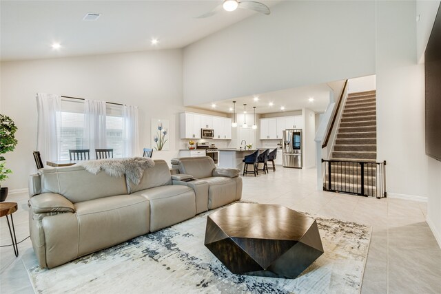 tiled living room featuring ceiling fan and high vaulted ceiling