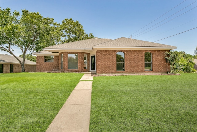 single story home featuring a shingled roof, a front lawn, and brick siding