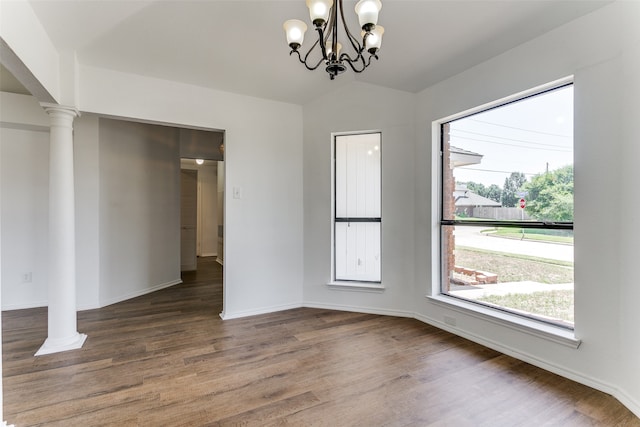 unfurnished dining area with lofted ceiling, decorative columns, baseboards, and wood finished floors