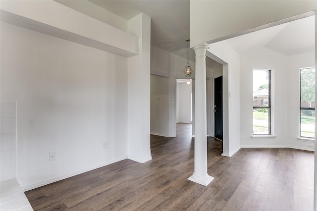 spare room featuring decorative columns, vaulted ceiling, and dark wood finished floors