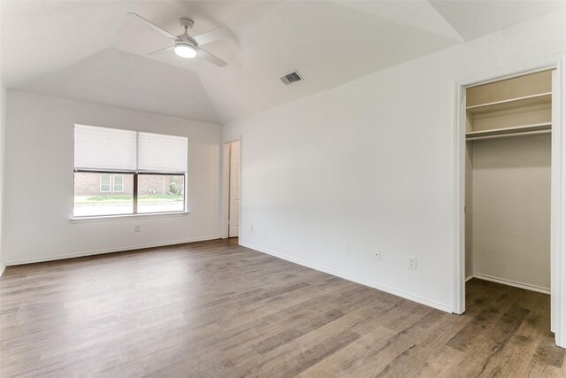 unfurnished bedroom featuring wood-type flooring, a closet, lofted ceiling, a spacious closet, and ceiling fan