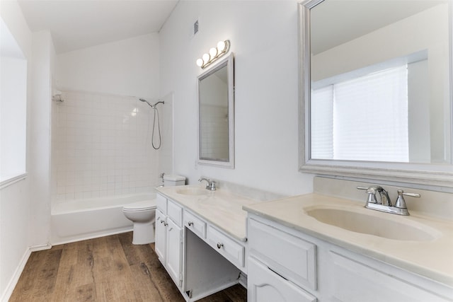 full bath featuring double vanity, a sink, toilet, and wood finished floors