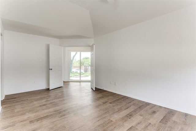 empty room with vaulted ceiling and light hardwood / wood-style floors