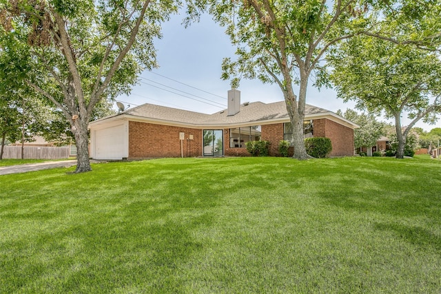 ranch-style house with brick siding, a chimney, an attached garage, and a front yard