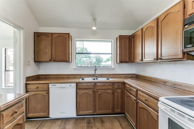 kitchen with white appliances, dark wood-style floors, brown cabinetry, and a sink