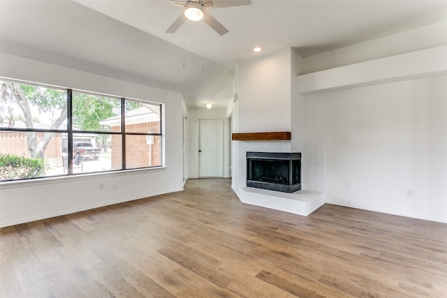 unfurnished living room with a tile fireplace, light hardwood / wood-style floors, ceiling fan, and high vaulted ceiling