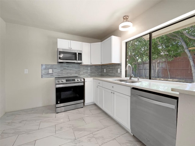 kitchen with sink, stainless steel appliances, white cabinetry, and decorative backsplash