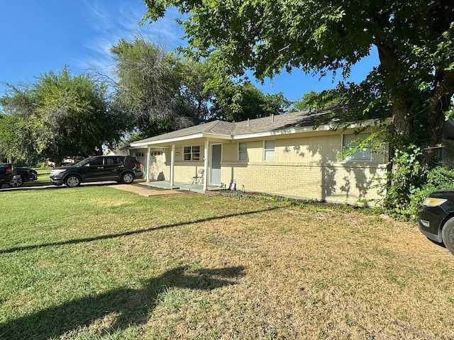 view of front of house featuring brick siding, a front lawn, and a garage
