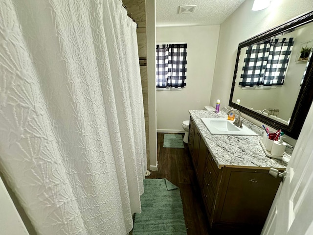 bathroom featuring a textured ceiling, toilet, vanity, and hardwood / wood-style floors