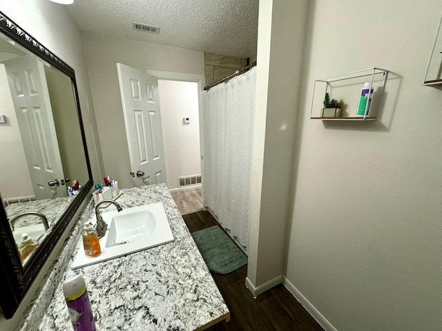 bathroom with a sink, visible vents, a textured ceiling, and wood finished floors