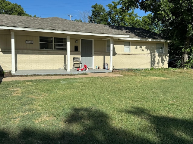 view of front facade featuring brick siding, roof with shingles, and a front lawn