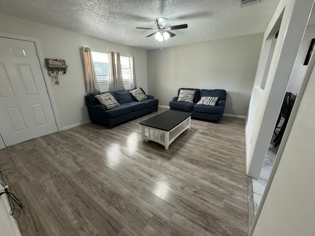 living room with ceiling fan, a textured ceiling, and wood-type flooring