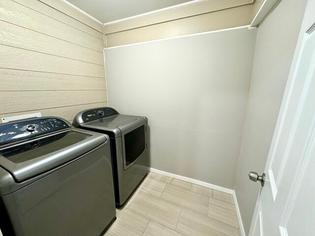 laundry room with washer and dryer, wooden walls, and light tile patterned floors