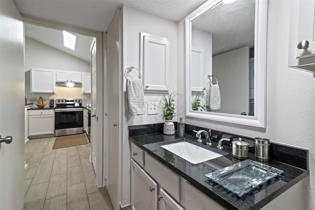 bathroom with a textured ceiling, vanity, and lofted ceiling with skylight