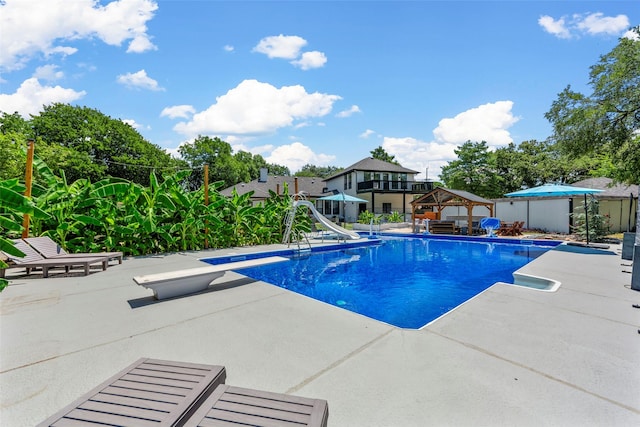 view of swimming pool featuring a gazebo, a water slide, a diving board, and a patio area