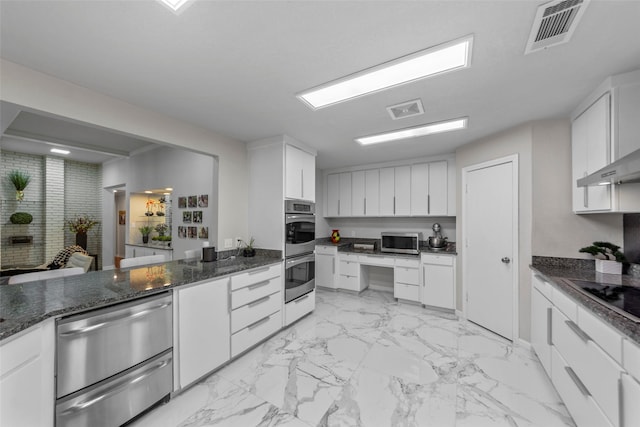 kitchen with white cabinets, stainless steel appliances, and dark stone counters