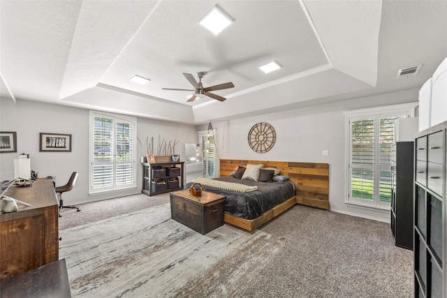 bedroom featuring ceiling fan, a raised ceiling, a textured ceiling, and carpet