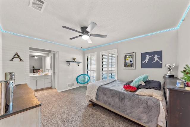 bedroom with ensuite bathroom, carpet floors, ceiling fan, and a textured ceiling