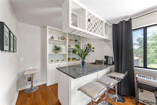 kitchen featuring a breakfast bar area, dark wood-type flooring, plenty of natural light, and kitchen peninsula