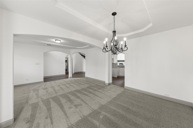 spare room featuring a raised ceiling and carpet