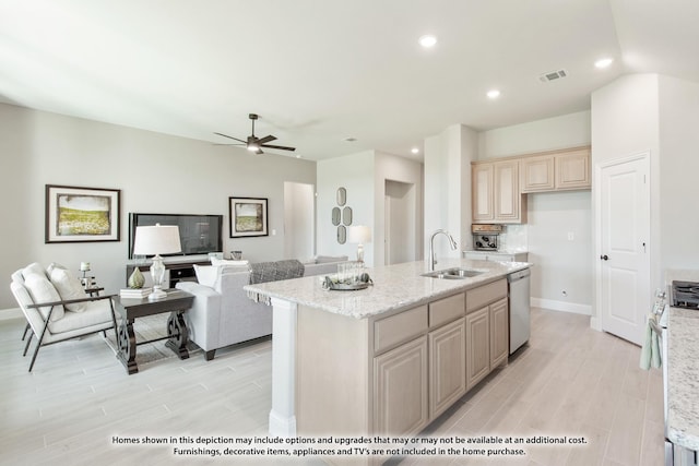 kitchen featuring a center island with sink, appliances with stainless steel finishes, light stone countertops, ceiling fan, and sink