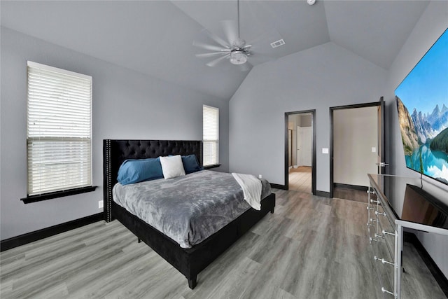 bedroom featuring ceiling fan, light hardwood / wood-style floors, lofted ceiling, and multiple windows