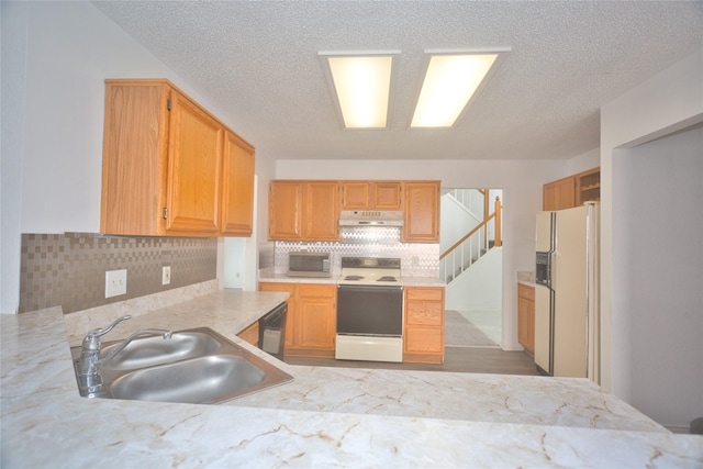 kitchen with tasteful backsplash, white appliances, sink, and a textured ceiling