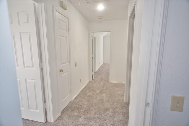 corridor with light colored carpet and a textured ceiling