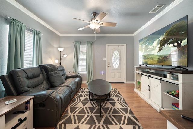 living room featuring ornamental molding, a textured ceiling, ceiling fan, and light wood-type flooring